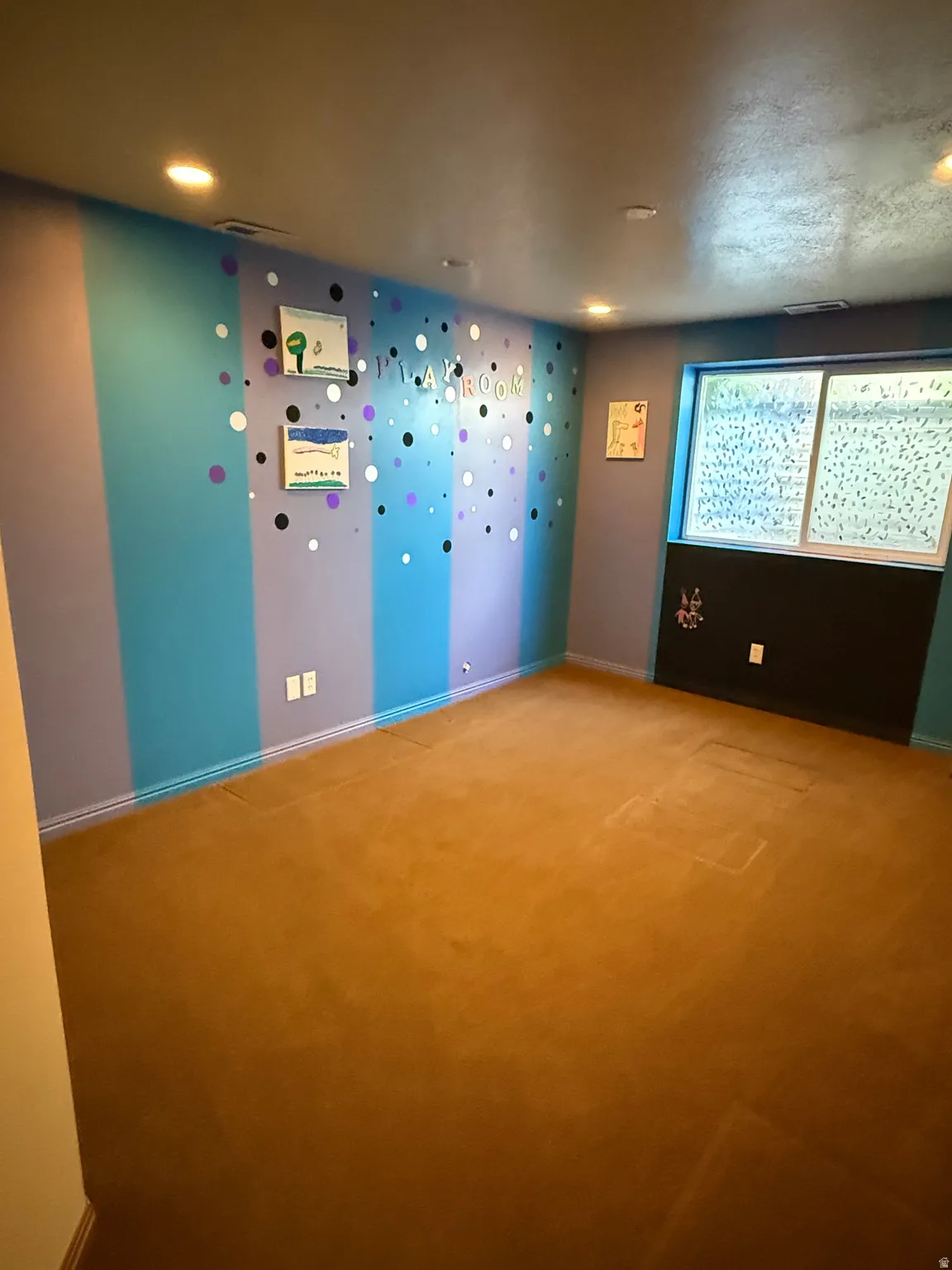 Carpeted interior space featuring recessed lighting, a window with obscured glass, and a wall with striped accent painting
