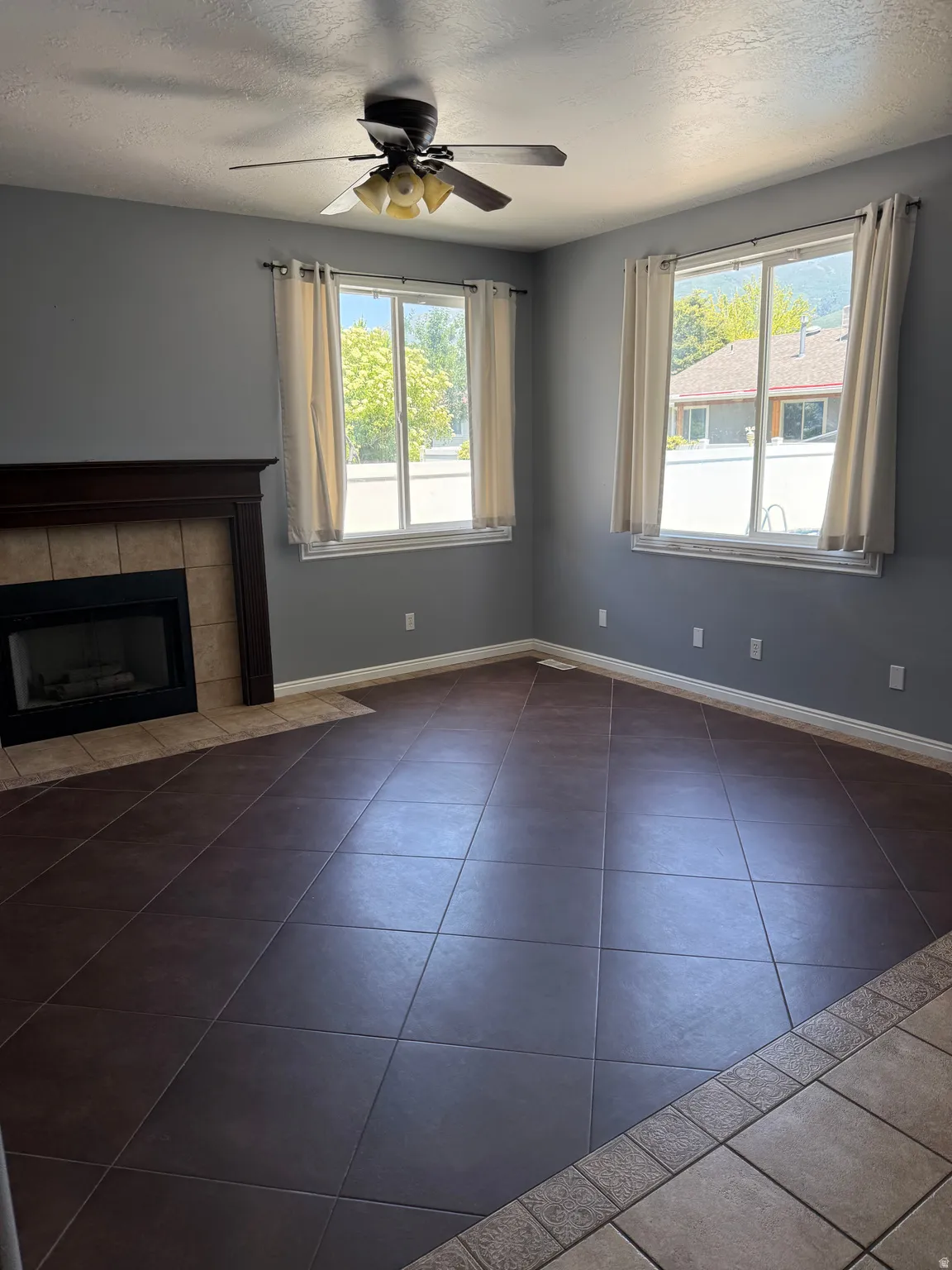 Spacious room featuring dark tile flooring and a fireplace with a wood mantel