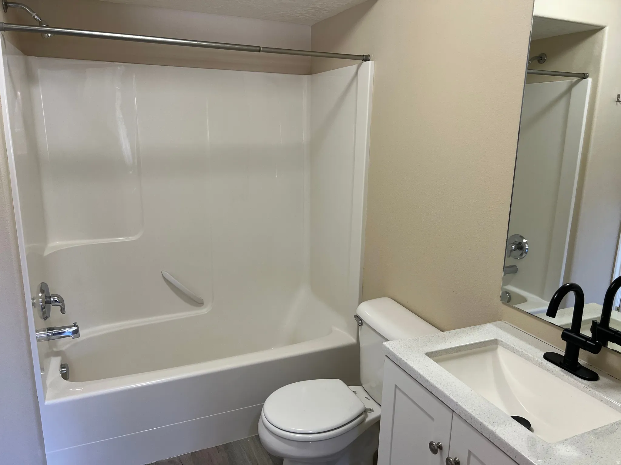 Full bathroom featuring vanity, washtub / shower combination, and dark wood-type flooring