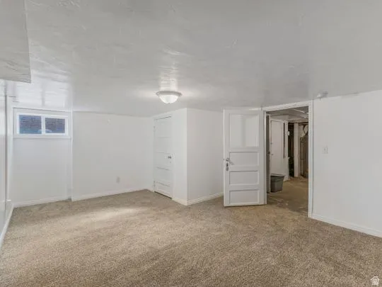 Finished below grade area featuring light colored carpet and baseboards