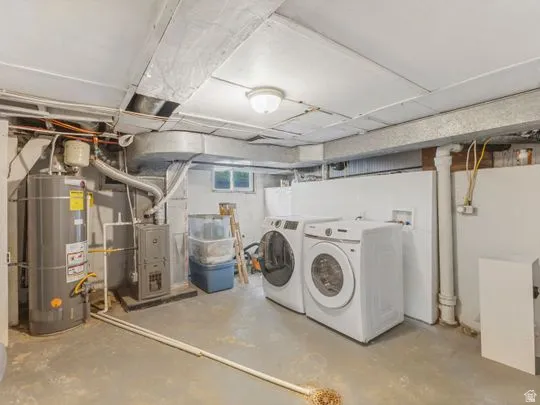 Below grade area with water heater, separate washer and dryer, and heating unit