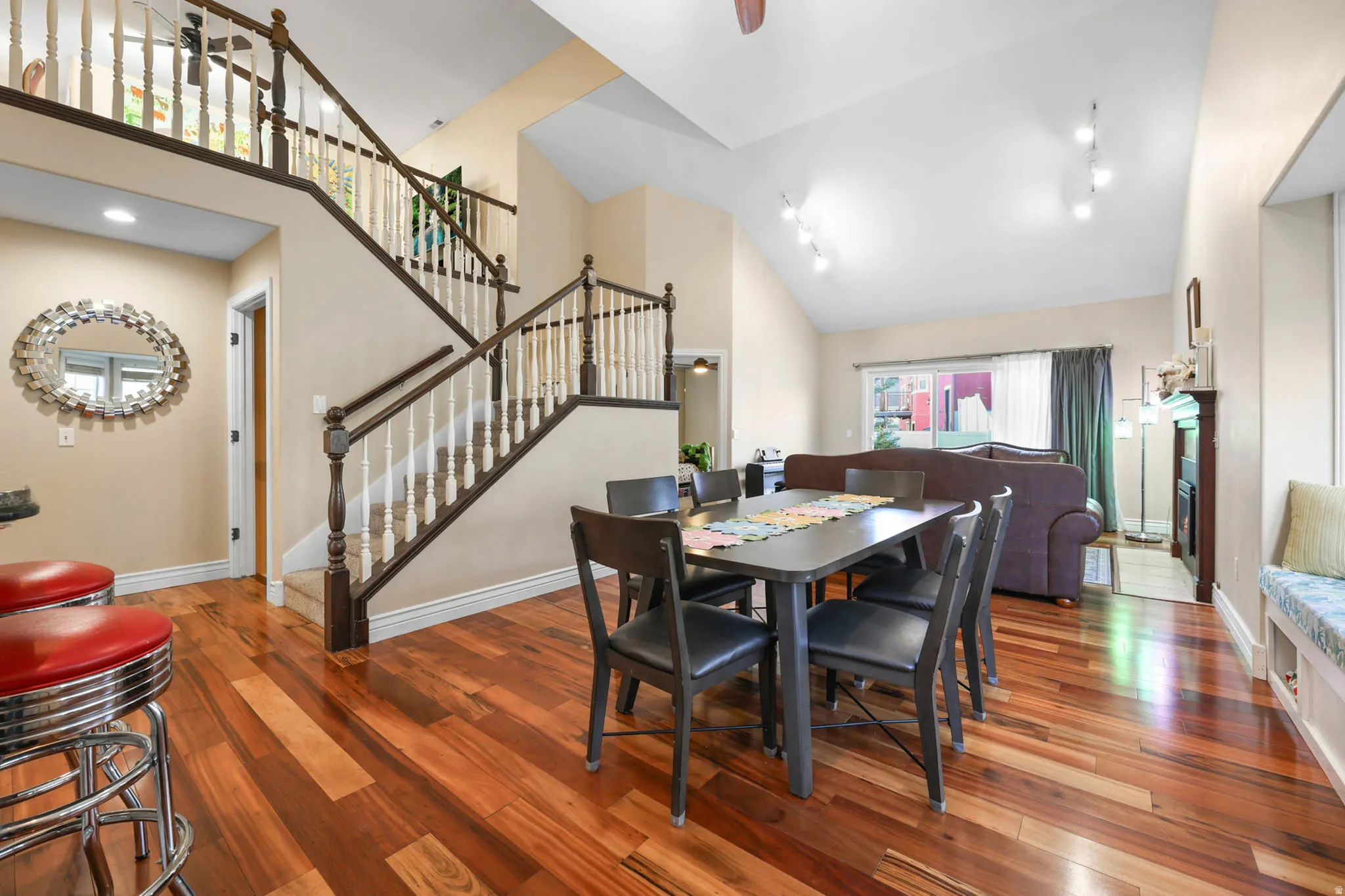 Dining area featuring hardwood / wood-style flooring, ceiling fan, vaulted ceiling, a fireplace, and rail lighting