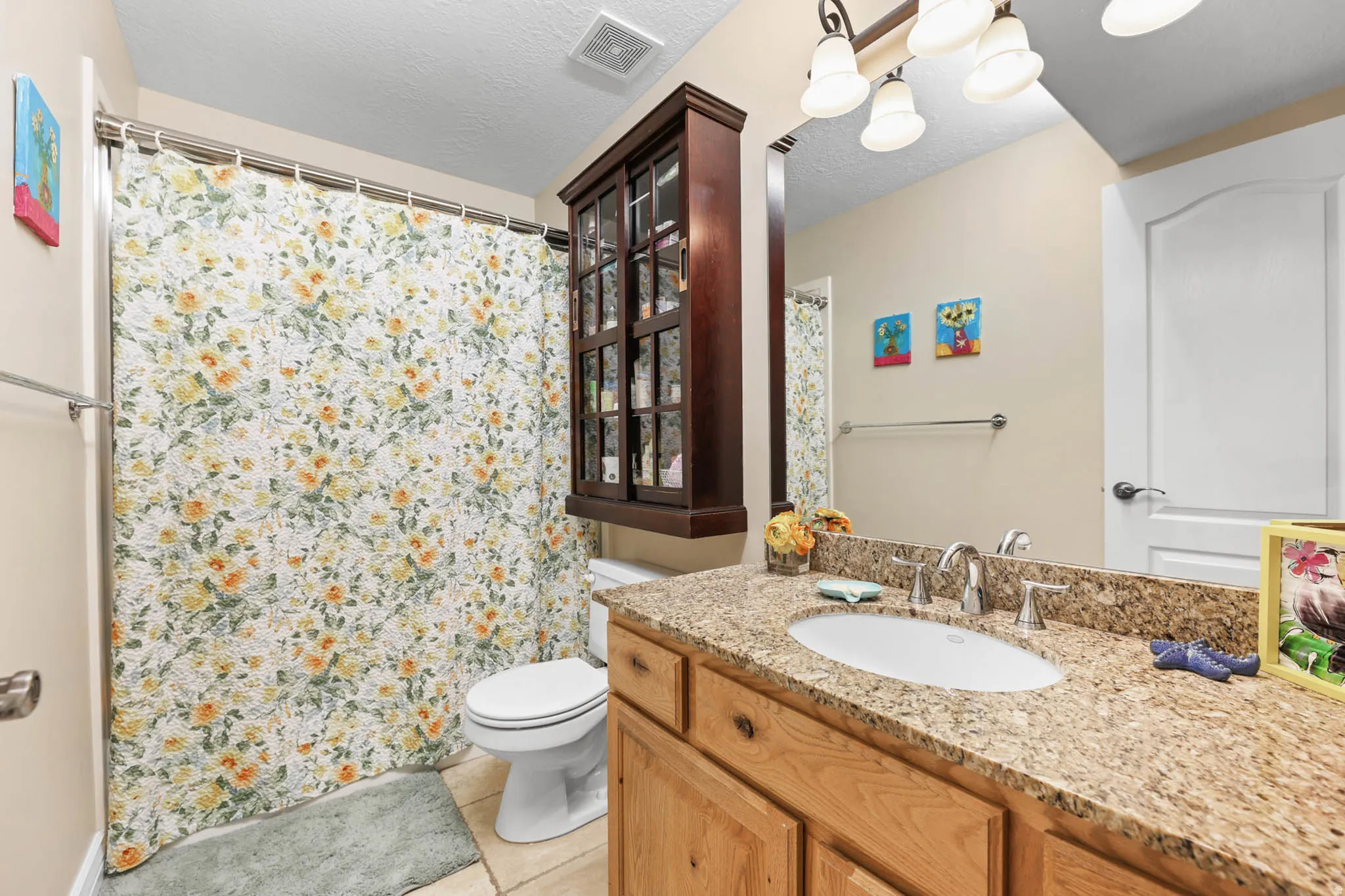 Bathroom with vanity, a shower with shower curtain, a textured ceiling, and light tile patterned floors
