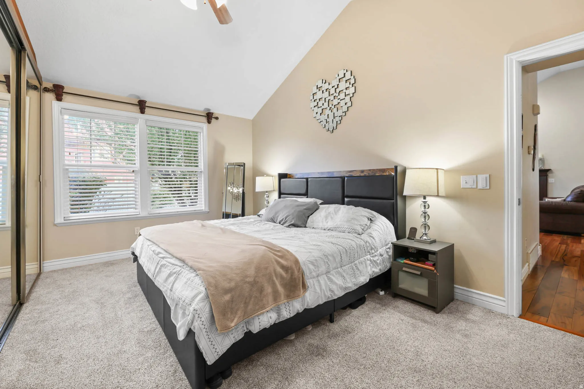 Bedroom featuring light colored carpet, vaulted ceiling, and a ceiling fan