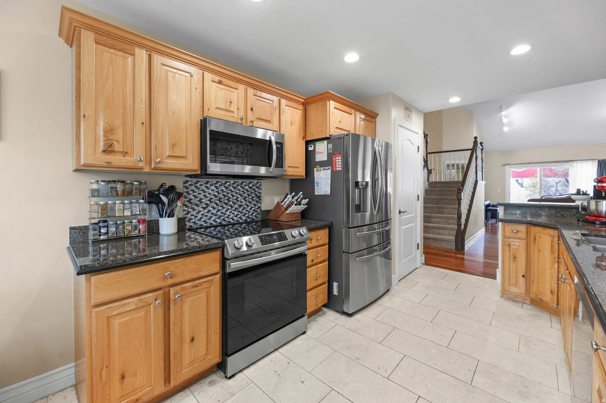 Kitchen featuring stainless steel appliances, dark stone counters, decorative backsplash, and recessed lighting