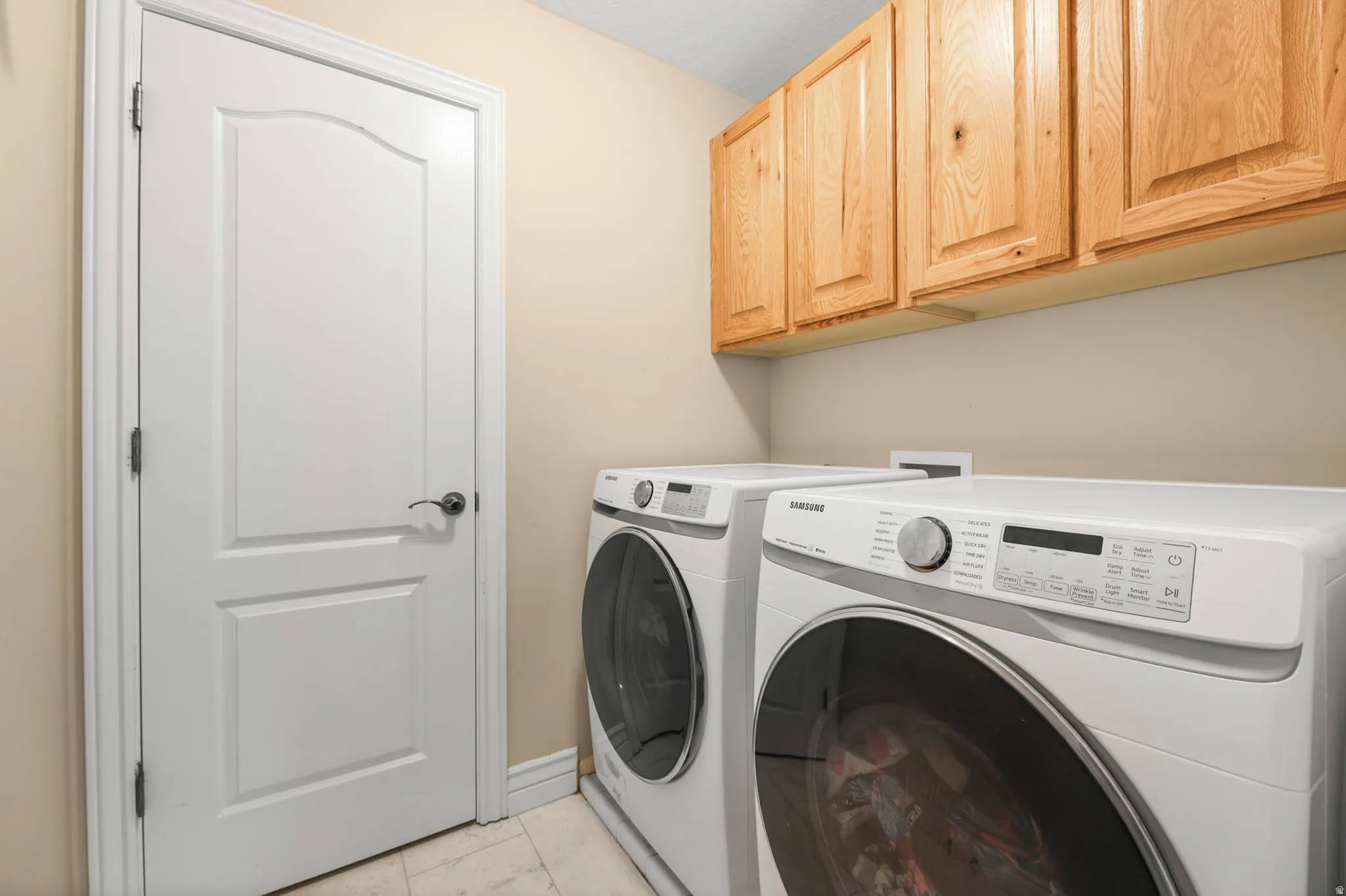 Laundry room with washer and clothes dryer, cabinet space, and light tile patterned floors