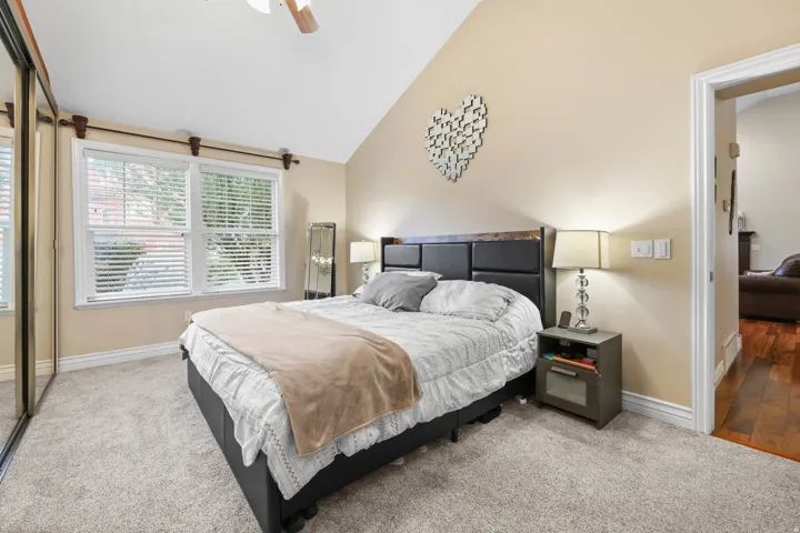 Bedroom featuring light colored carpet, vaulted ceiling, and a ceiling fan