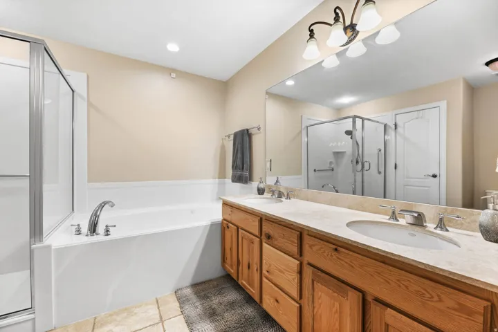 Bathroom featuring double vanity, a stall shower, a garden tub, light tile patterned floors, and recessed lighting