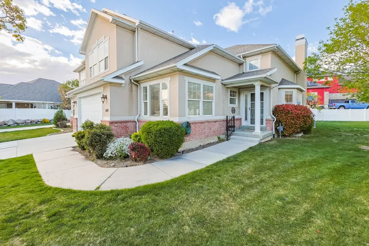 Traditional home featuring brick siding, stucco siding, an attached garage, and a chimney