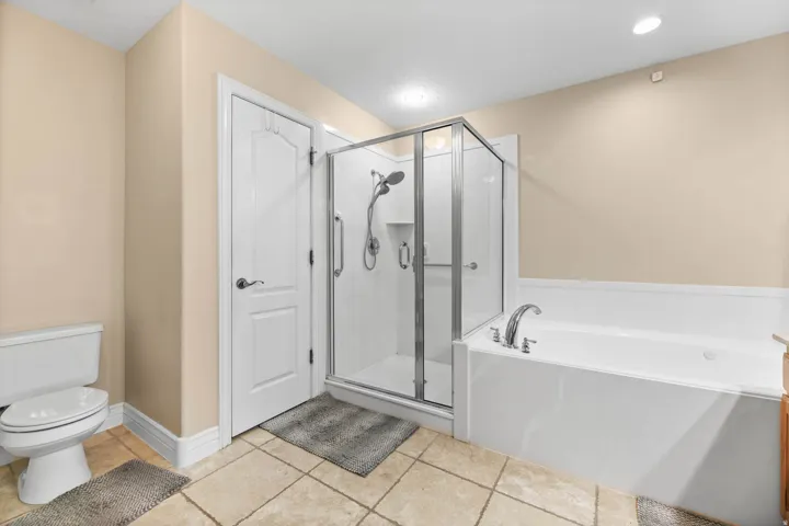 Bathroom featuring a stall shower, a garden tub, and light tile patterned floors