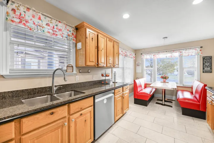 Kitchen featuring stainless steel dishwasher, dark stone countertops, and decorative light fixtures