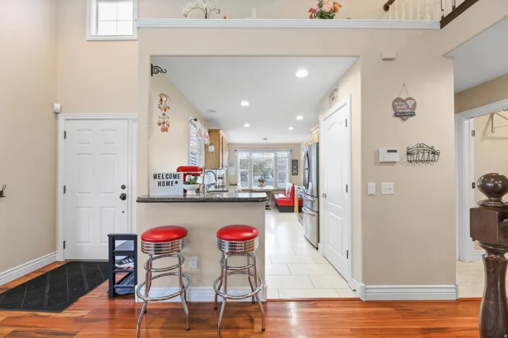 Kitchen with dark stone countertops, a peninsula, light wood-style floors, freestanding refrigerator, and recessed lighting