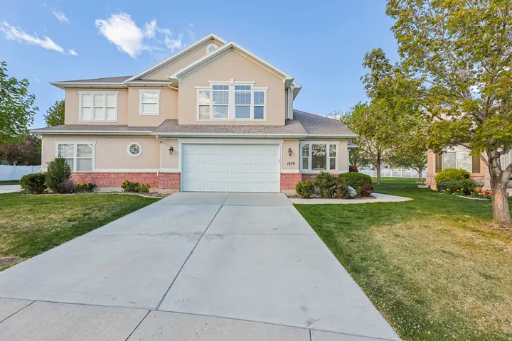 View of front of house featuring stucco siding, an attached garage, brick siding, and a front yard