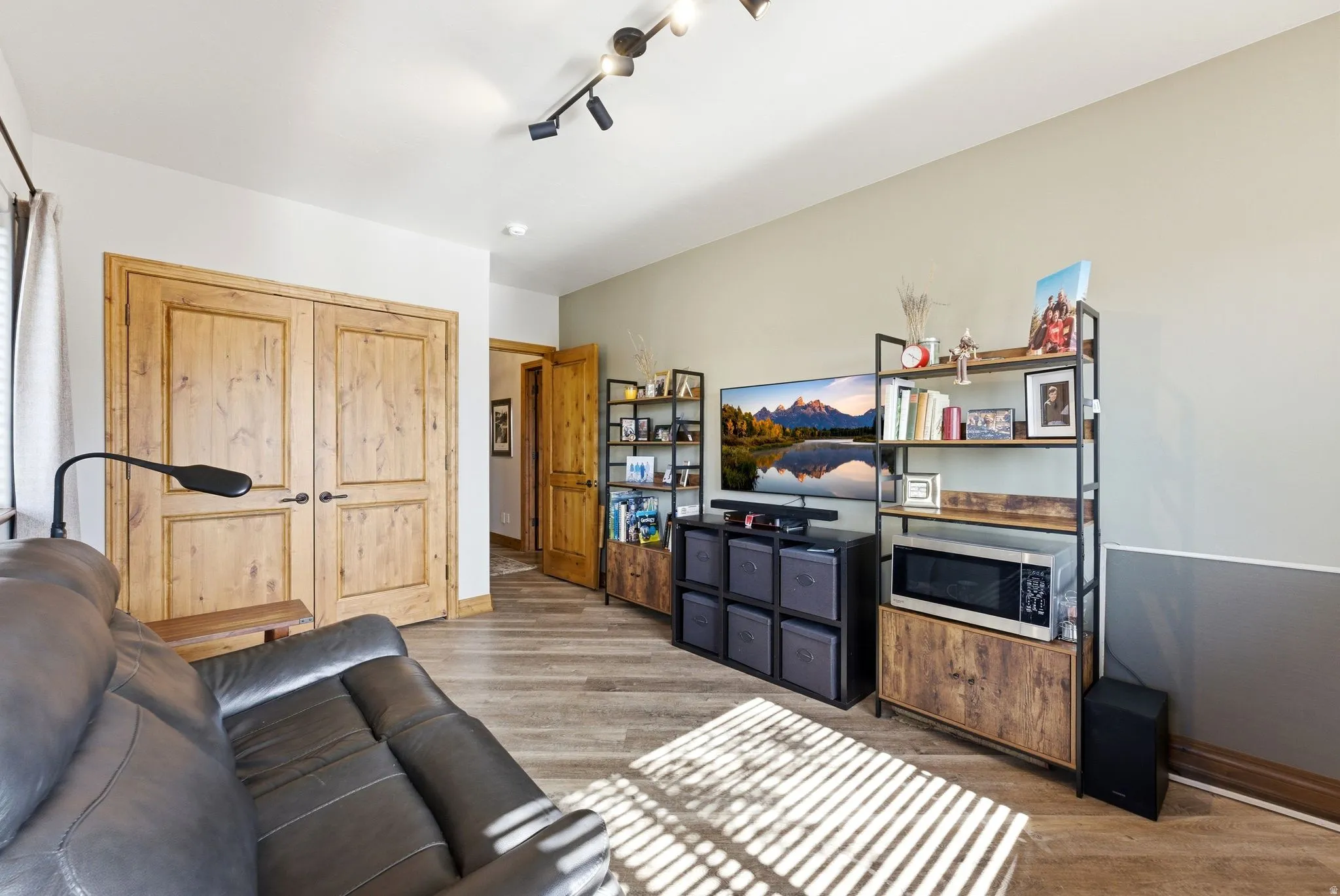 Living area with light wood-type flooring and rail lighting
