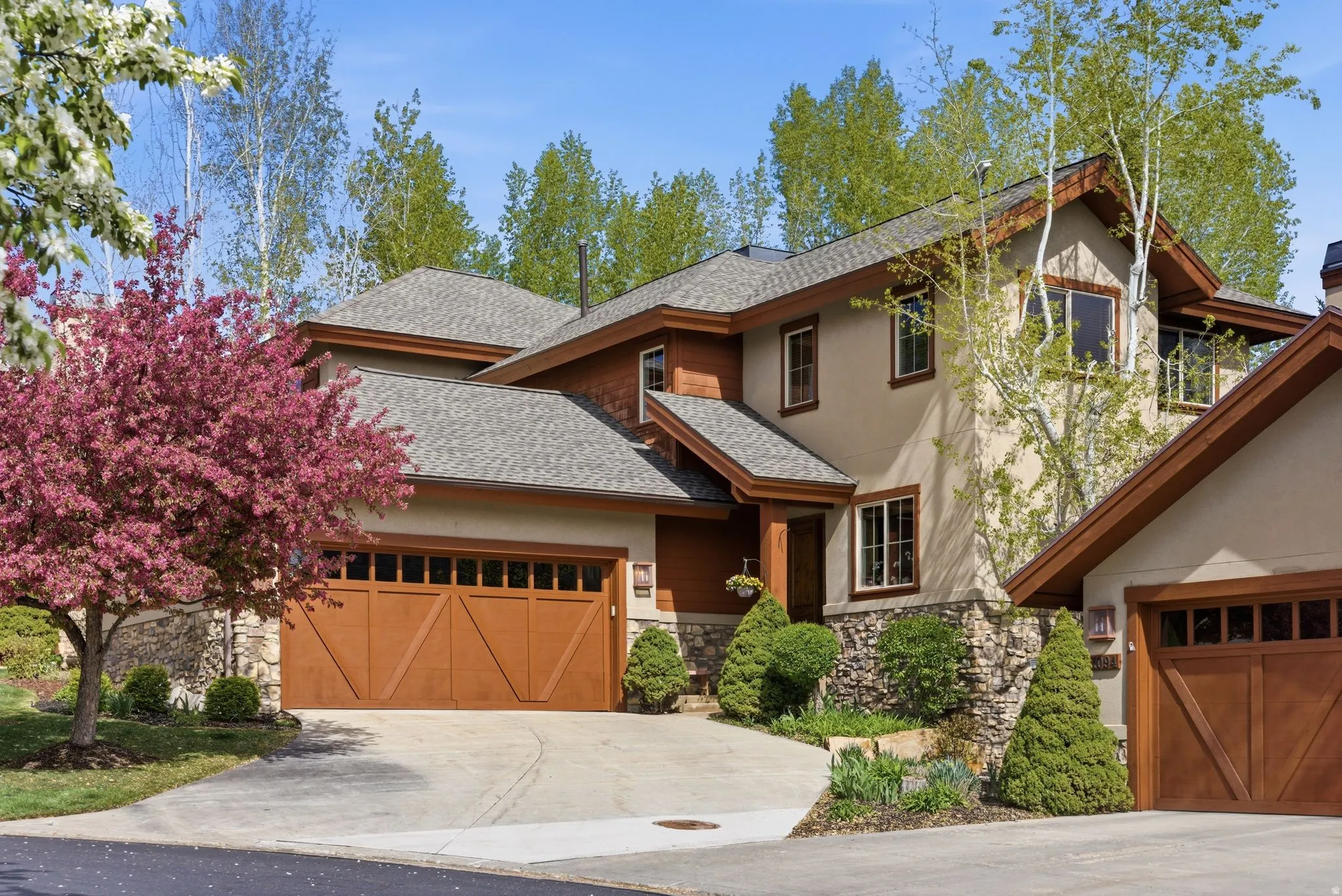 View of front of house featuring stone siding, a shingled roof, an attached garage, concrete driveway, and stucco siding
