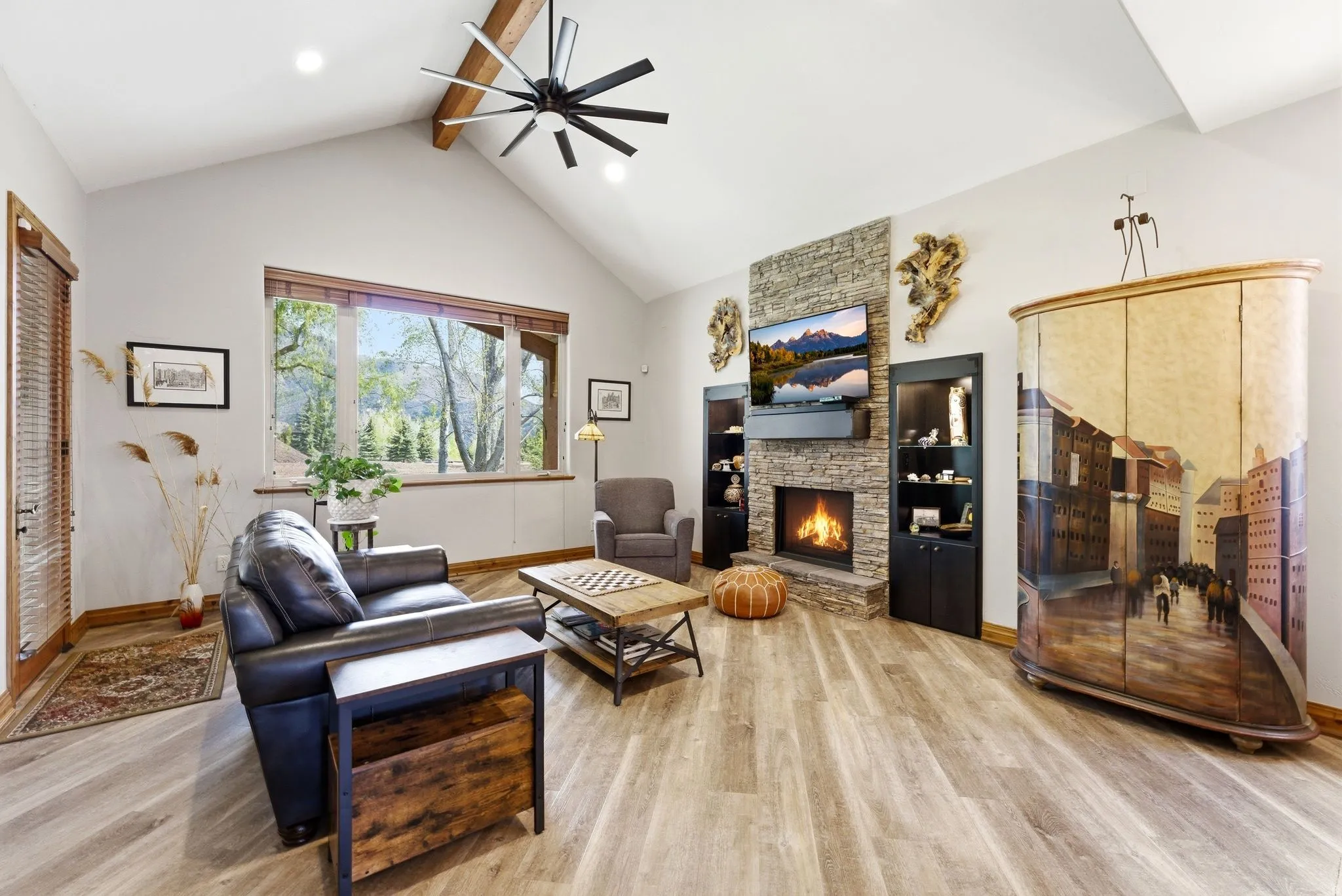 Living room featuring a stone fireplace, light wood finished floors, and a ceiling fan