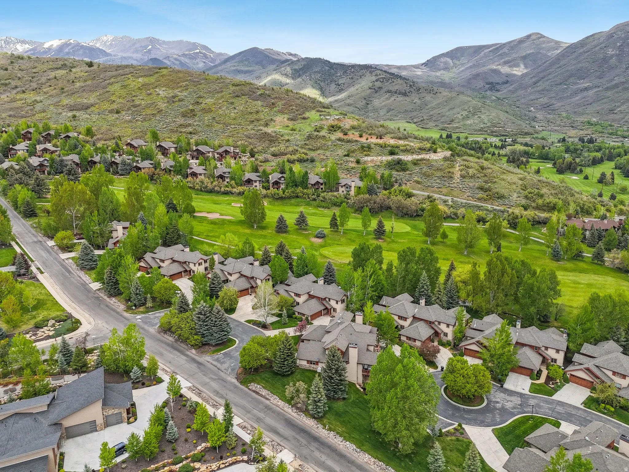 Aerial perspective of suburban area with mountains and a golf course