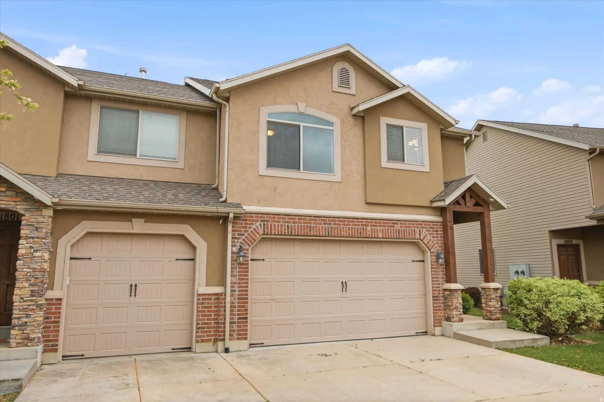Traditional home featuring stucco siding, driveway, an attached garage, and brick siding