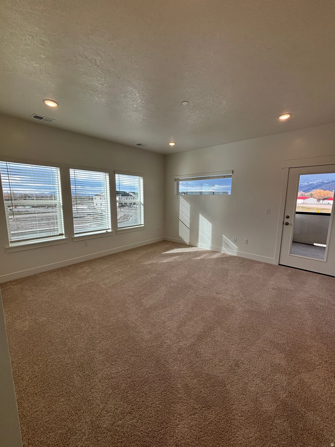 Carpeted spare room featuring a textured ceiling and recessed lighting