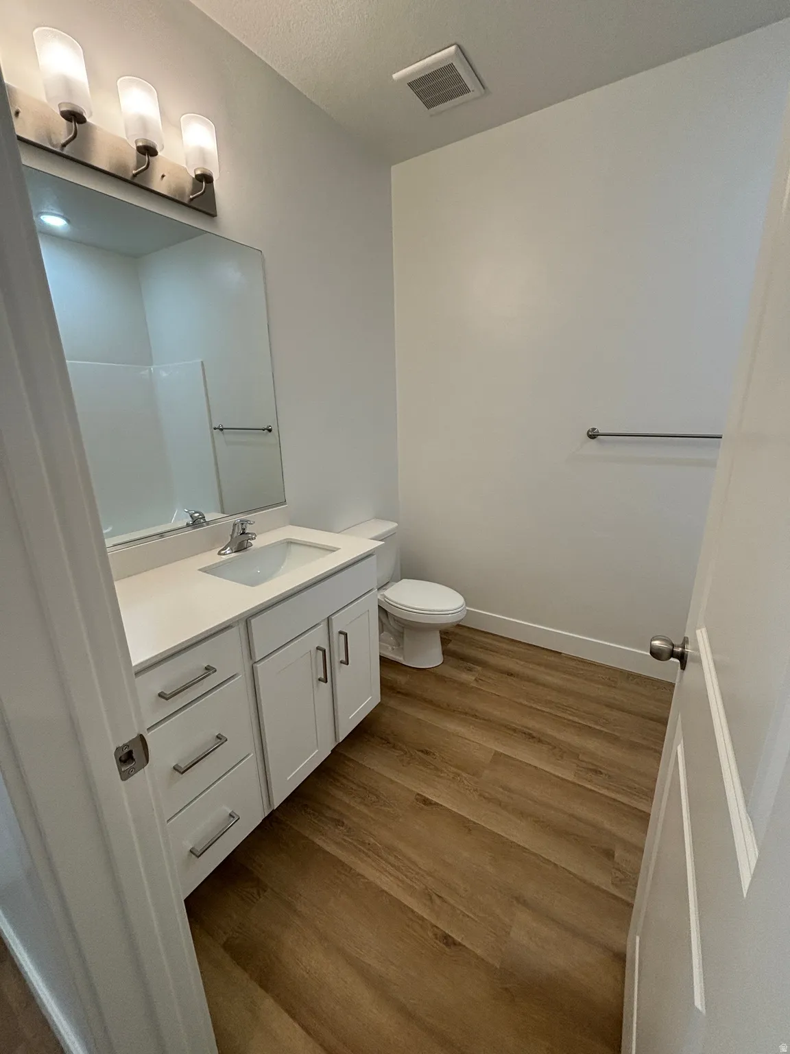 Full bath with vanity and dark wood-style floors