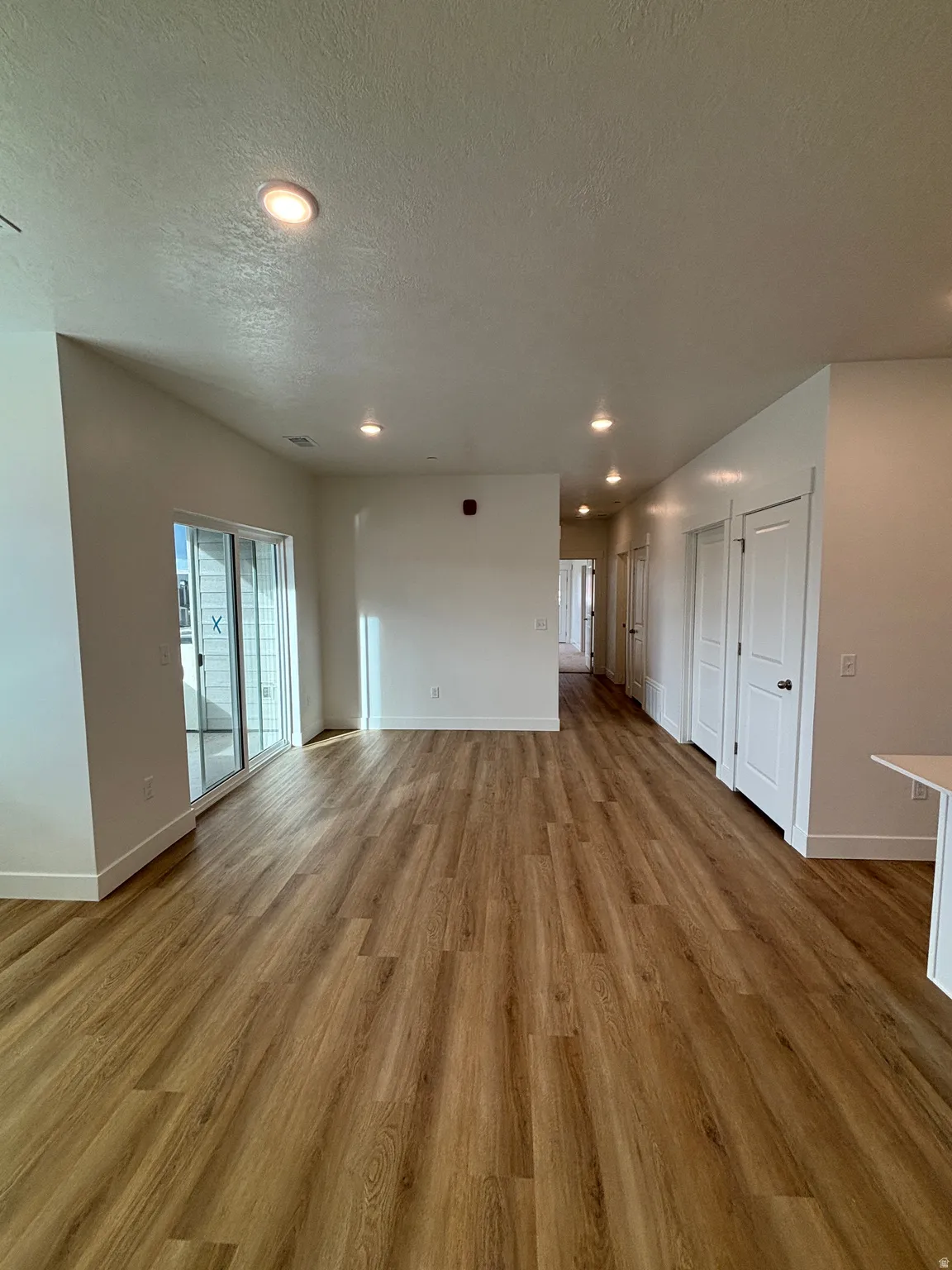 Unfurnished living room featuring recessed lighting, light wood-style flooring, and a textured ceiling