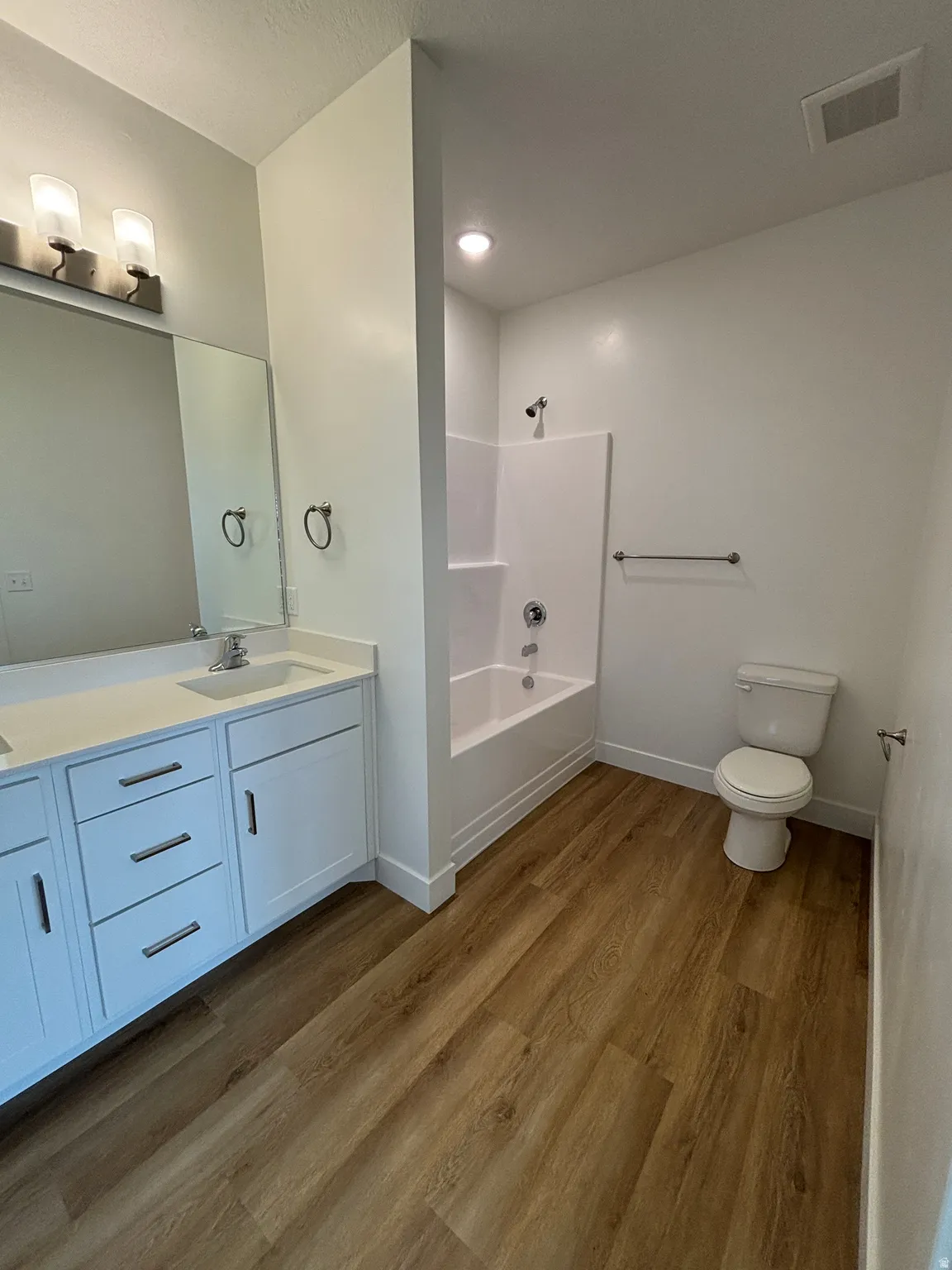 Full bath featuring double vanity, dark wood finished floors, and shower / bath combination