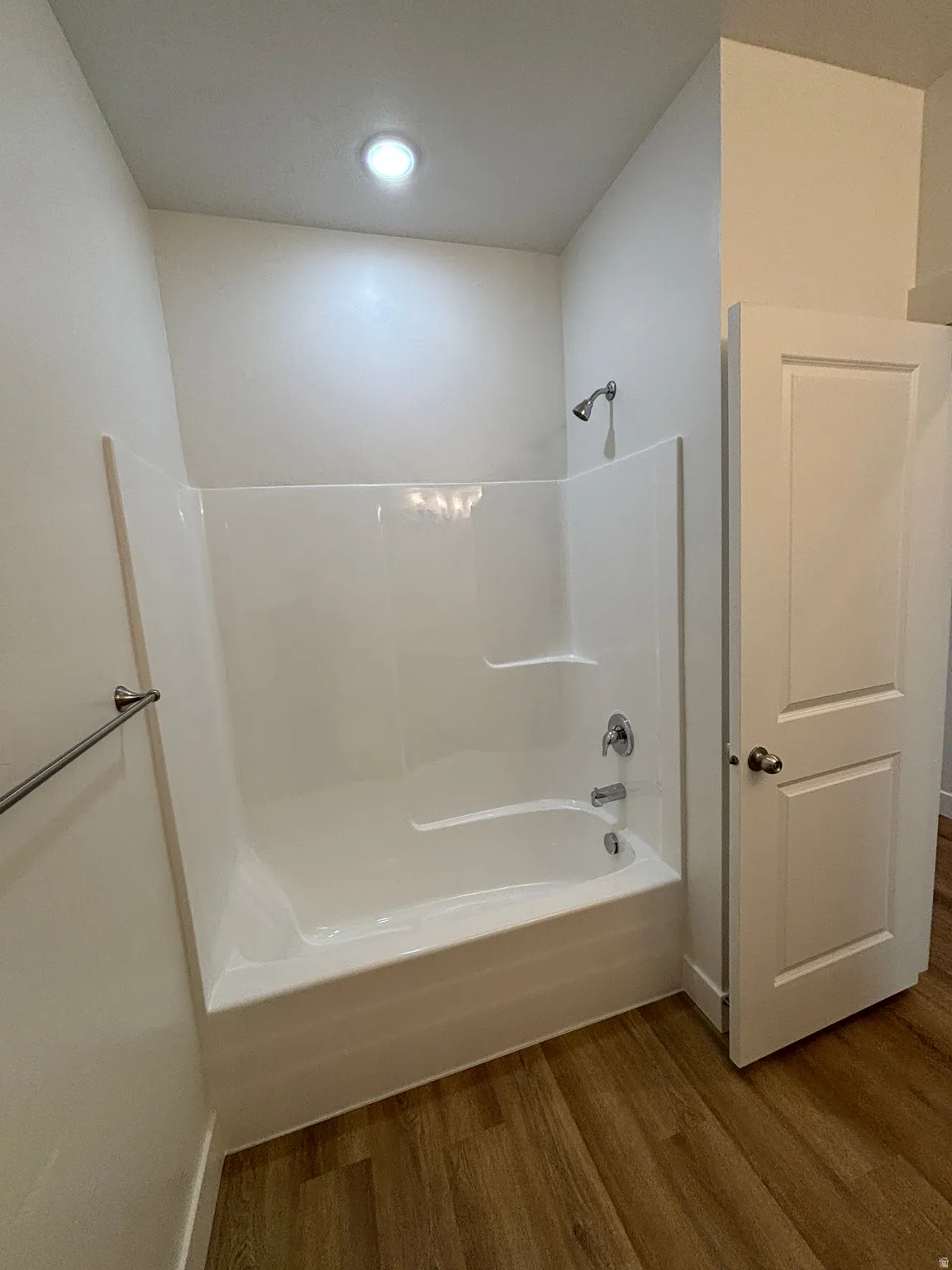 Bathroom with dark wood-type flooring, shower / bath combination, and recessed lighting