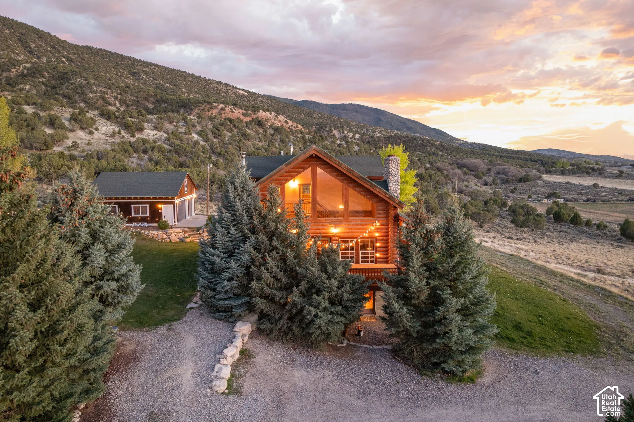 View of front of house with a mountain view, a chimney, log exterior, covered porch, and a lawn