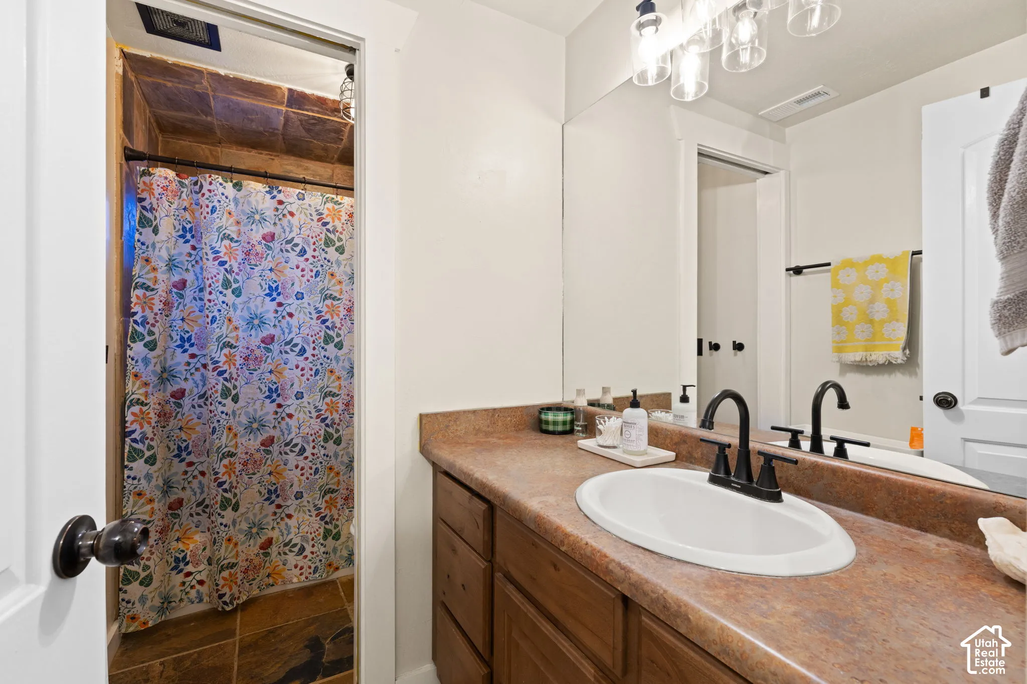 Full bath with vanity, a shower with shower curtain, and dark stone finish floors