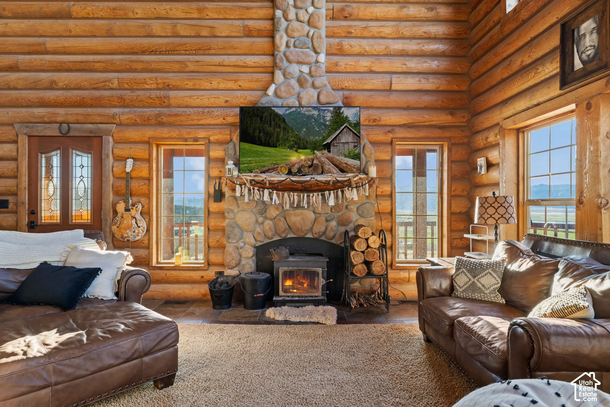 Living room with a fireplace and rustic walls, ample natural lighting