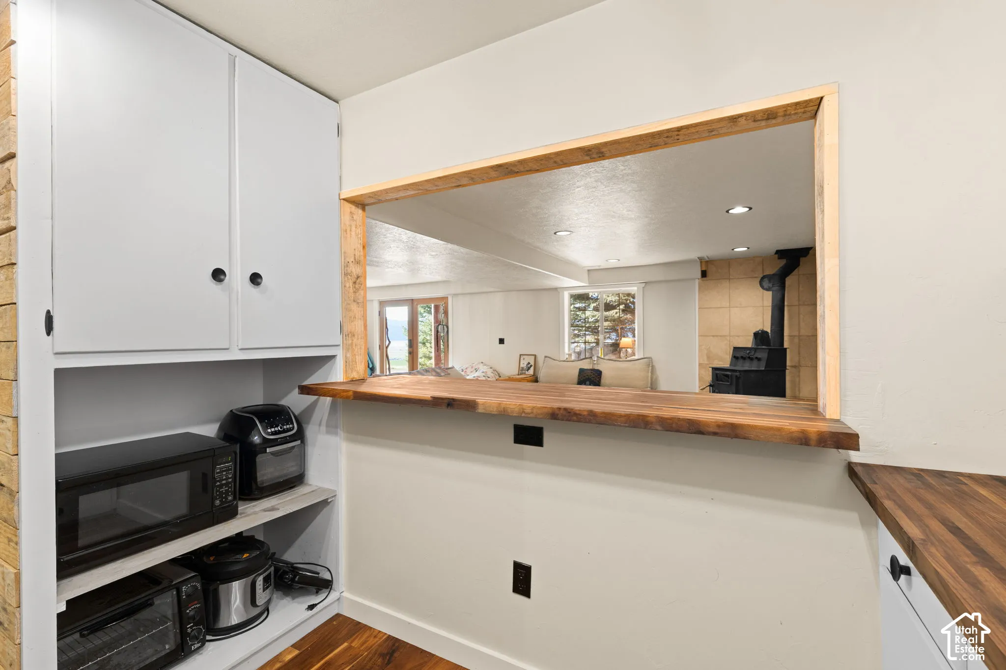 Kitchenette featuring a breakfast bar area, refrigerator with ice dispenser, white cabinets, dark wood finished floors, and recessed lighting