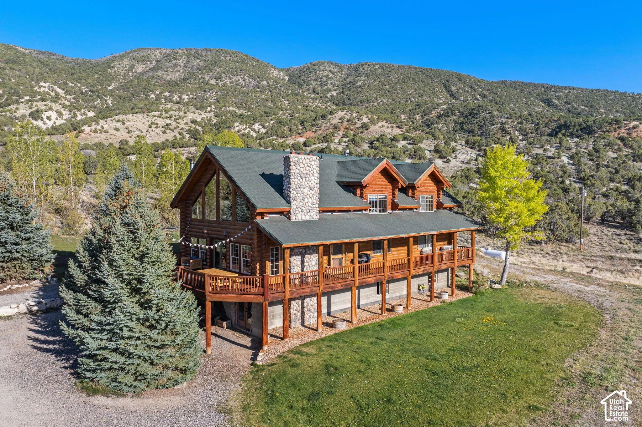 Back of house featuring a chimney, a mountain view, covered porch, a yard, and log siding