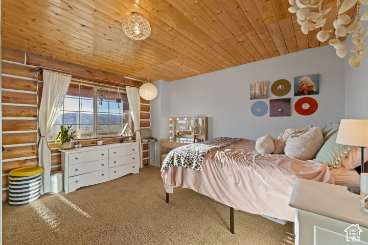 Bedroom with carpet, log walls, and wooden ceiling