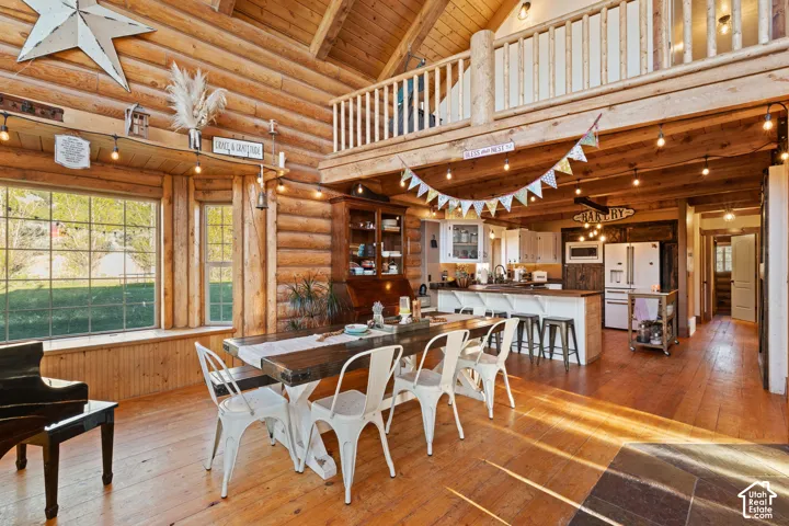 Dining area with a high wood beamed ceiling, rustic walls, and light wood-style floors