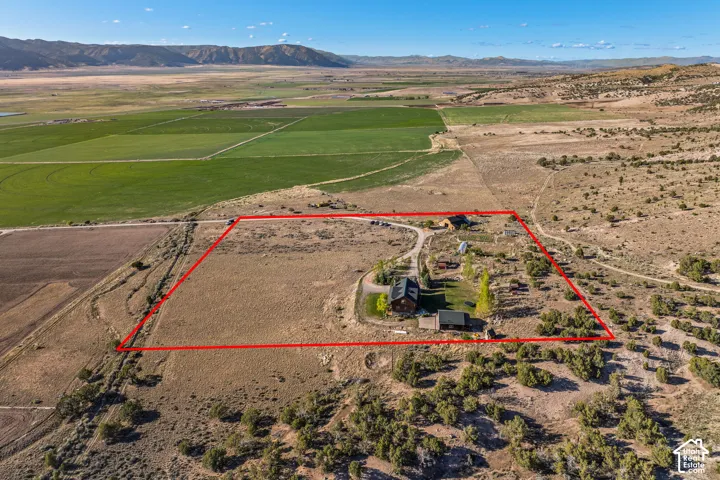 Aerial view of sparsely populated area with property parcel outlined and a mountainous background