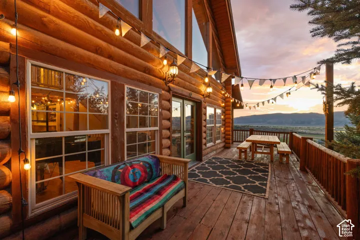 Deck at dusk with a mountain view, french doors, and outdoor dining area