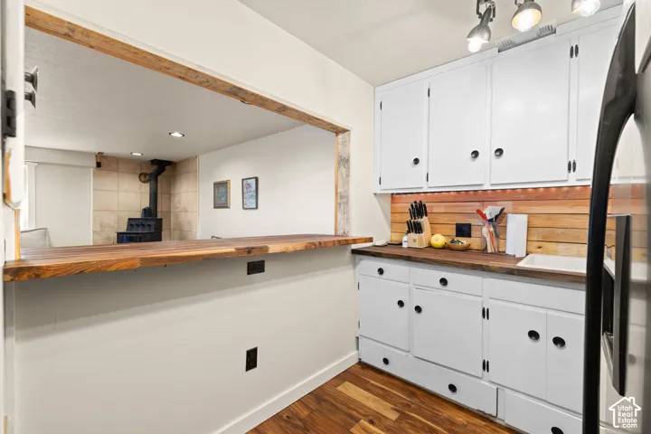 Kitchenette featuring a breakfast bar area, refrigerator with ice dispenser, white cabinets, dark wood finished floors, and recessed lighting