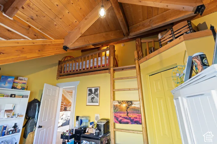Bedroom featuring log walls, wooden ceiling, light wood-type flooring, lofted ceiling with beams, and a closet with an upper loft area