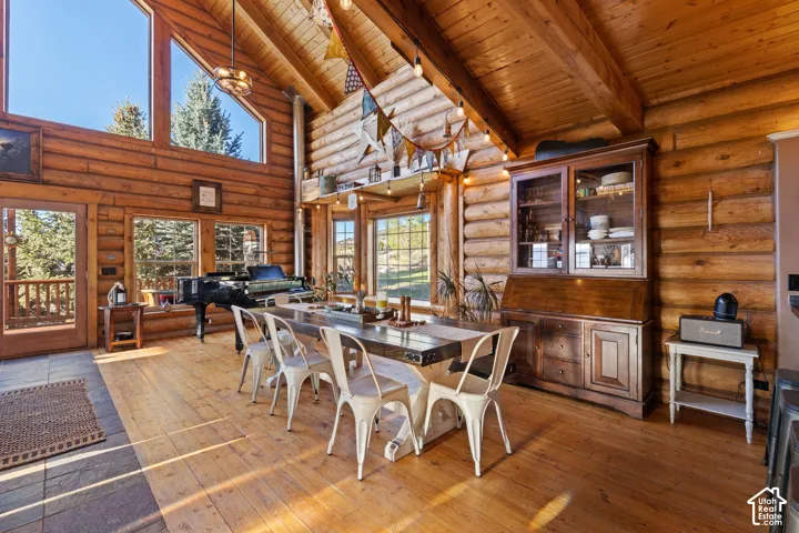 Dining space with a high wood beamed ceiling, light wood-type flooring, and log walls