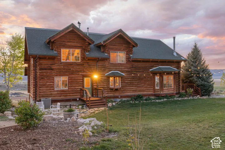 Log home featuring log exterior, a shingled roof, and a yard