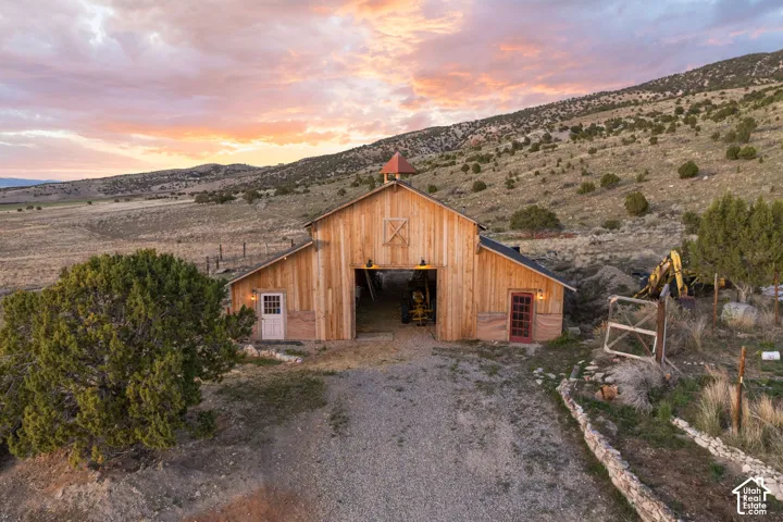 Outdoor structure at dusk with a barn, a mountain view, and driveway