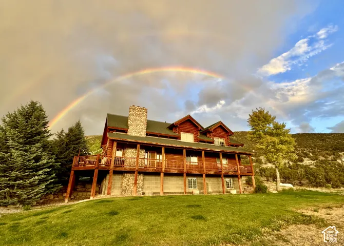 Log cabin exterior featuring a stone chimney, extensive wooden decking, and a pitched roof