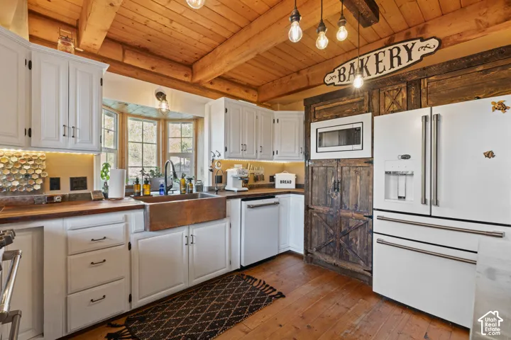 Kitchen featuring wood counters, high-end cafe appliances, dark wood-style floors, white cabinets, and a wood ceiling with exposed beams