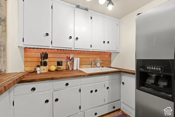 Kitchenette featuring a breakfast bar area, refrigerator with ice dispenser, white cabinets, dark wood finished floors, and recessed lighting