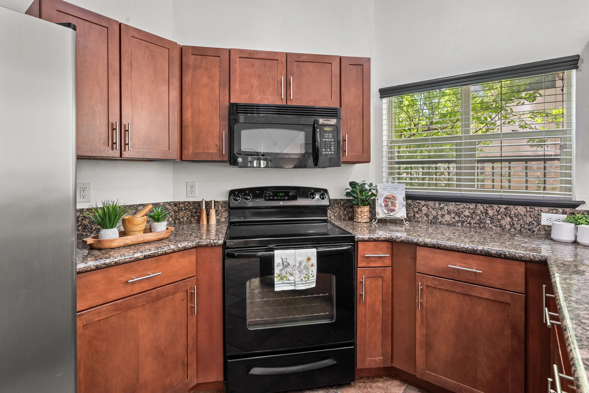 Kitchen featuring black appliances, dark stone countertops, and wood finish cabinetry