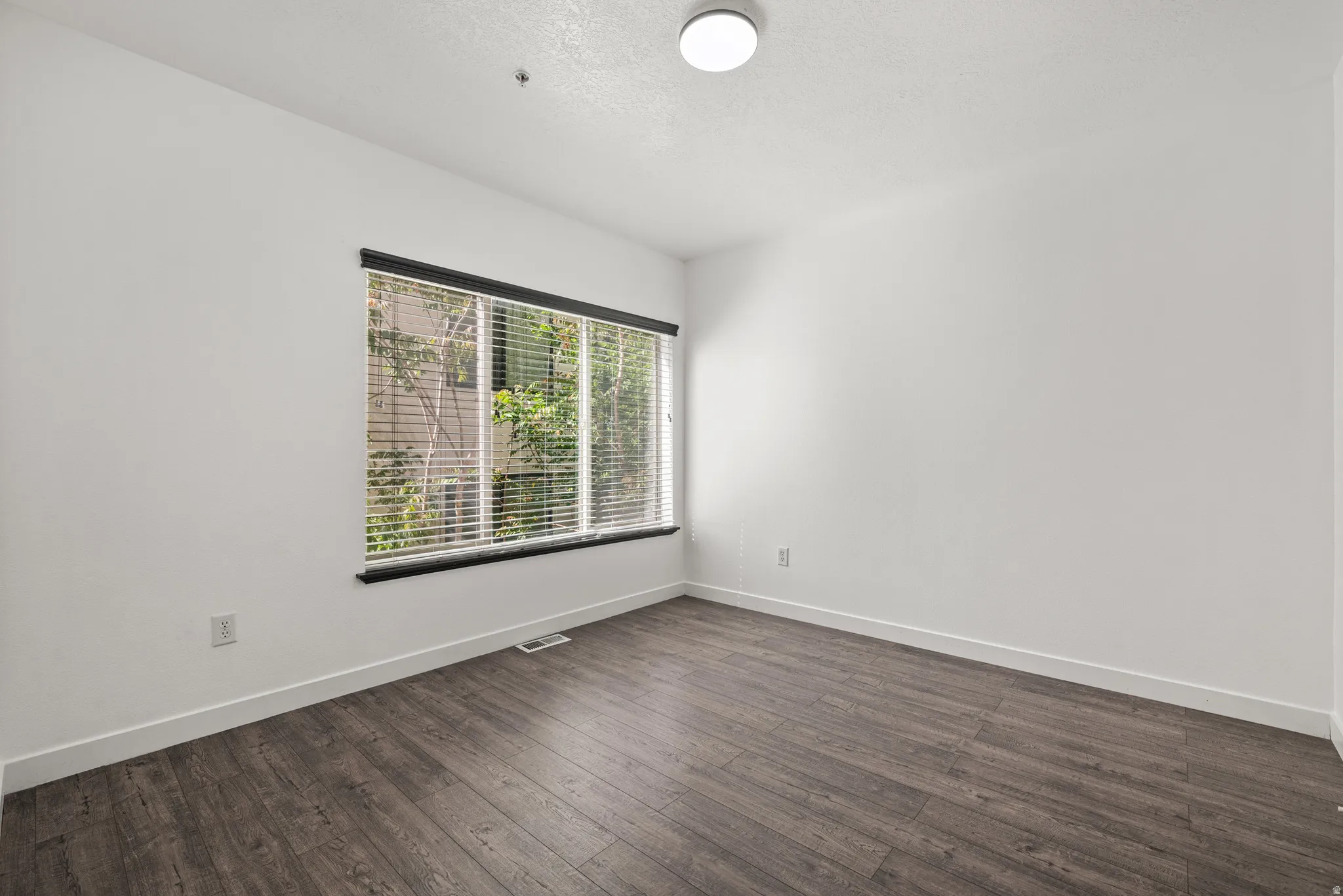 Unfurnished room with dark wood-style floors and a textured ceiling