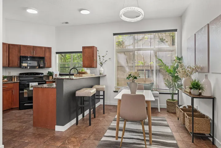 Kitchen featuring black appliances, dark stone countertops, a breakfast bar area, a peninsula, and wood finish cabinetry