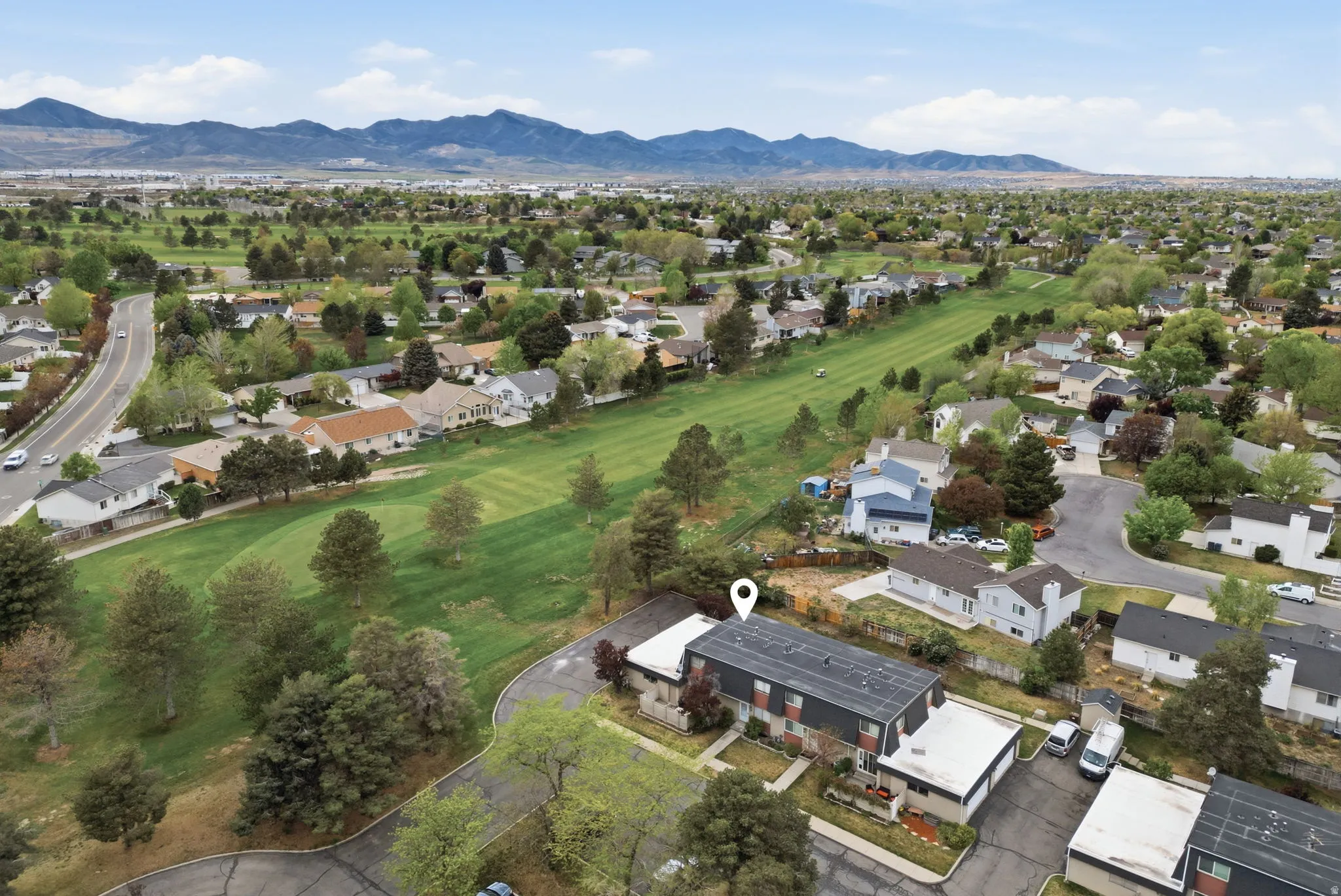 Aerial view of residential area featuring a mountainous background and a golf club