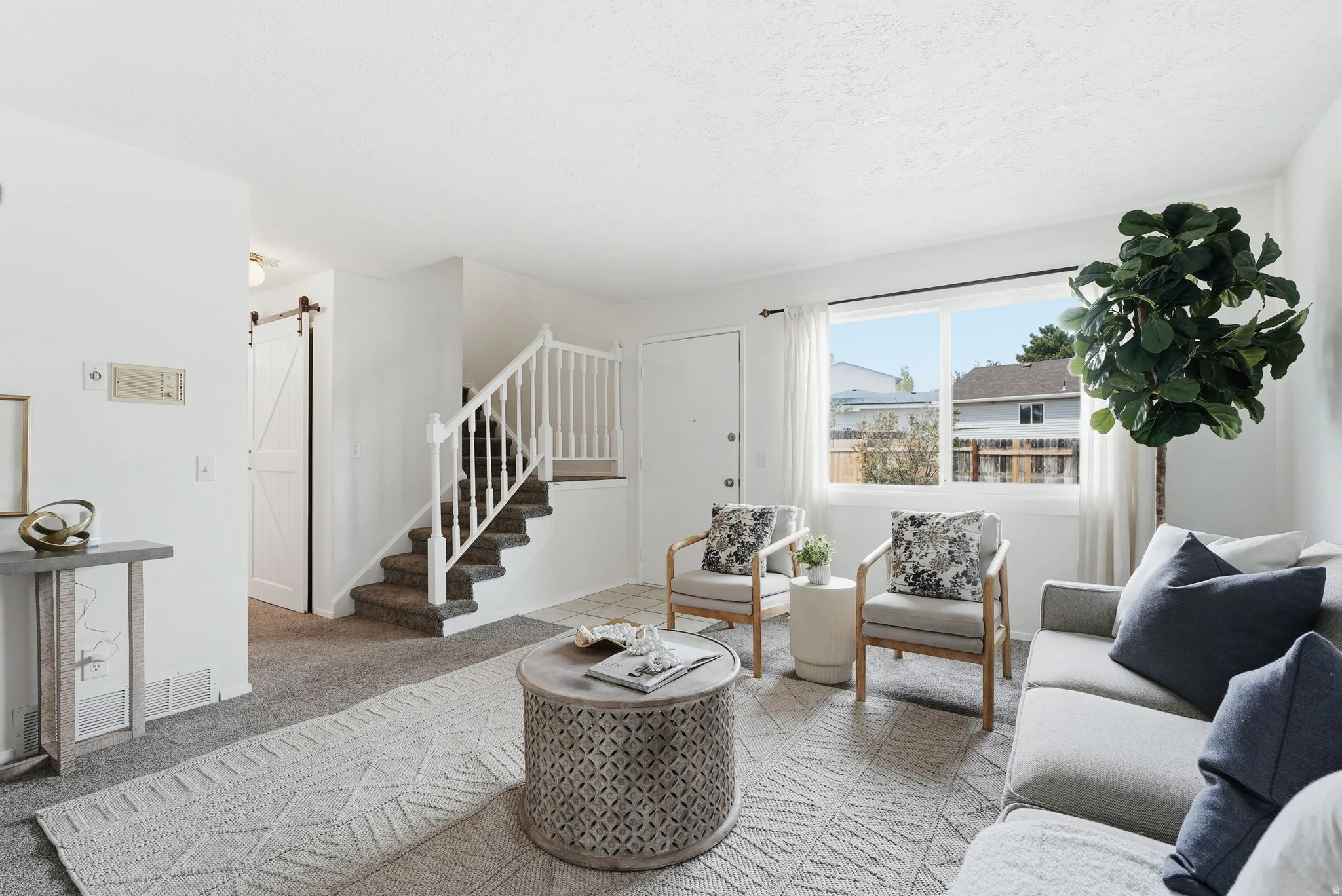 Carpeted living room featuring a barn door and stairway