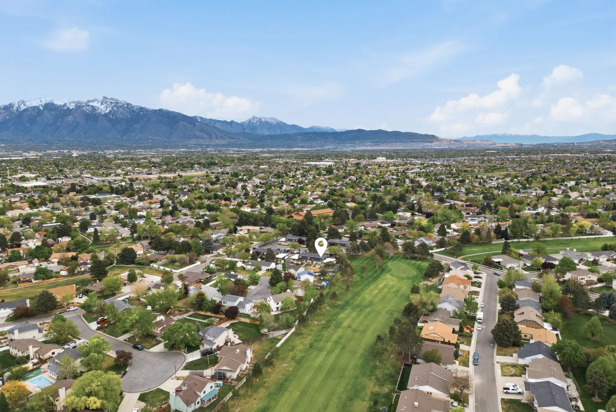 Aerial perspective of suburban area featuring a mountainous background and a golf club